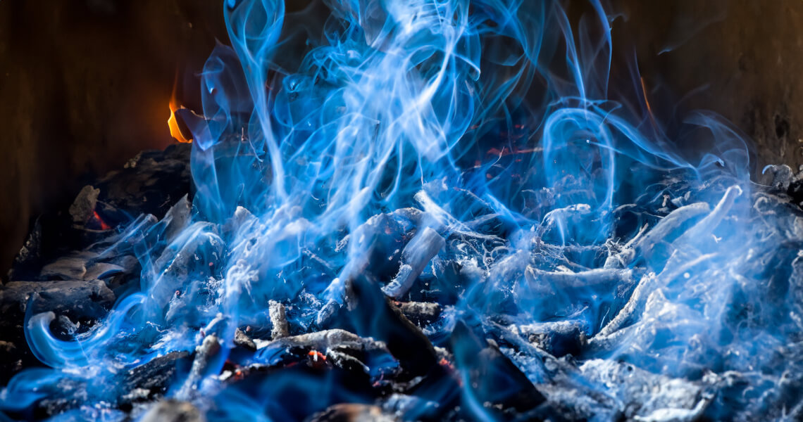 Blue smoke rising from burning ashes